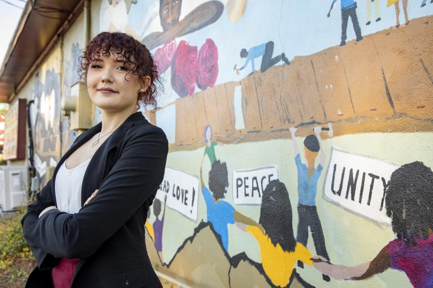 Environmental portrait of undergraduate student Allison Reid at the Building Bridges mural on the Food for the Soul restaurant in Athens.